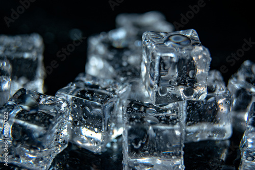 Group of some wet ice cubes isolated on black background. B/W photo
