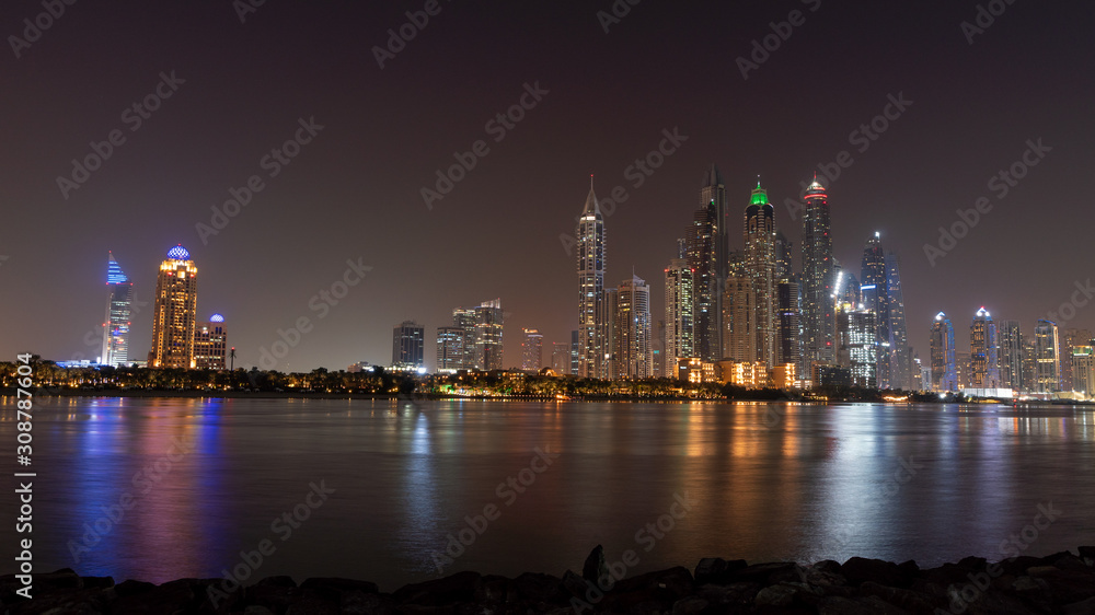 Naklejka premium Dubai skyline at night with lights on the water and luxirious skyscrapers of UAE