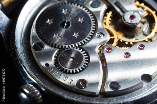 Antique wrist watch with metal gears and cogwheels. Detail of watch machinery, macro.