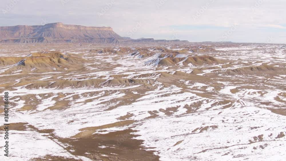 AERIAL: Flying over the snow covered desert and towards the stunning sandstone mountains in the remote parts of Utah. Breathtaking drone view of the barren Utah wilderness on a clear winter day. AERIAL: Flying over the snow covered desert and towards the stunning sandstone mountains in the remote parts of Utah. Breathtaking drone view of the barren Utah wilderness on a clear winter day.