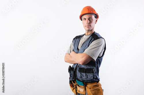 Builder with folded arms. In work clothes and hard hat.