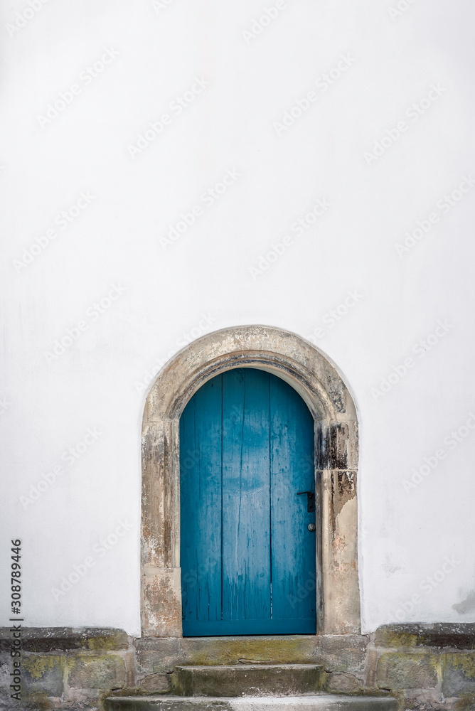 Fototapeta premium Arched wooden door. Old blue door and a white wall. Just a door