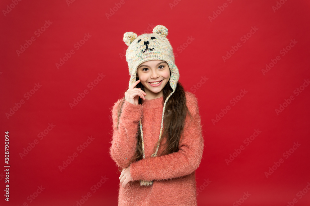 Obraz premium Happiness and joy. Winter outfit. Little kid wear knitted hat. Little girl winter fashion accessory. Small child long hair wear hat red background. Cute model enjoy winter style. Adorable small bear
