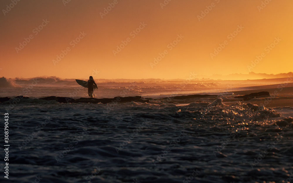 Woman surfing running into the surf at sunset