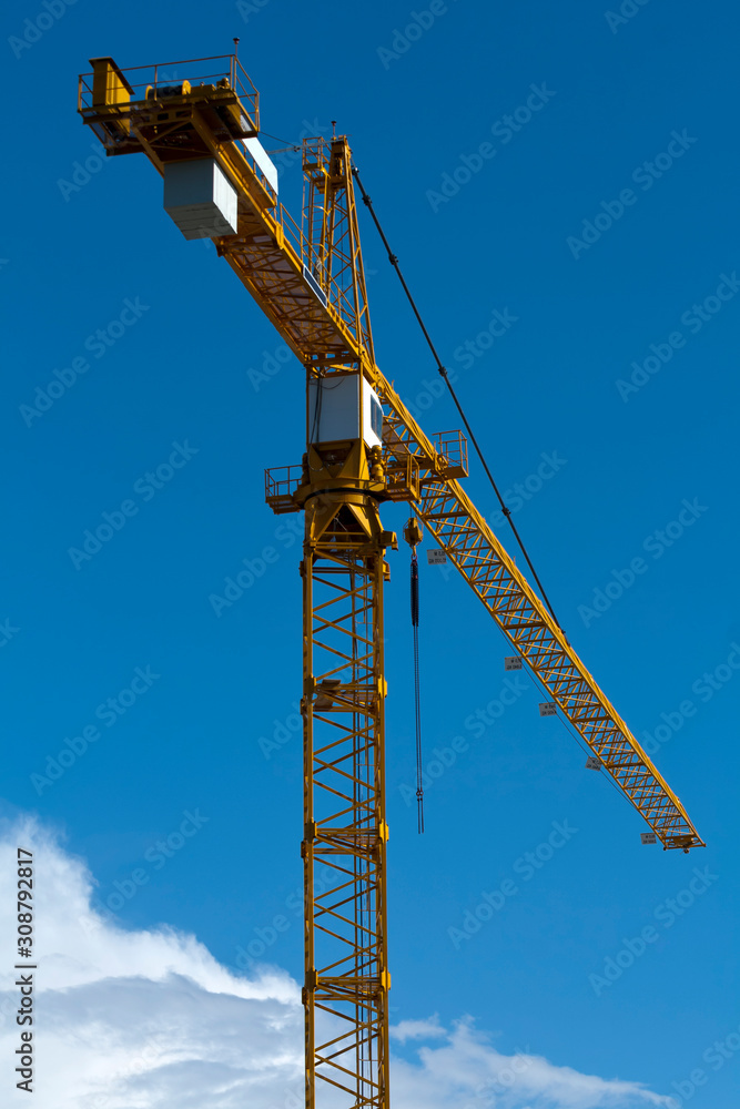 Yellow tower crane in front of blue sky Yellow tower crane in front of blue sky