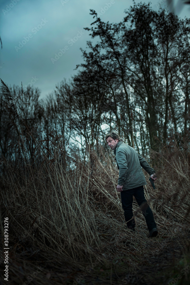 Man with pistol between reed on cloudy day. Man with pistol between reed on cloudy day.