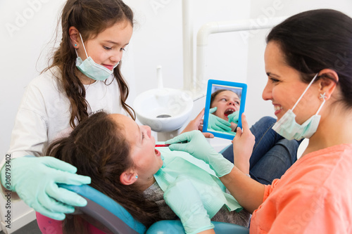Two little girls in dental surgery with cheerful female dentist