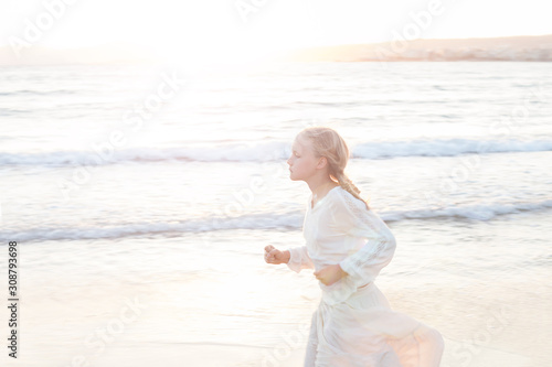 Blonde girl run at sunset on the beach in Europe