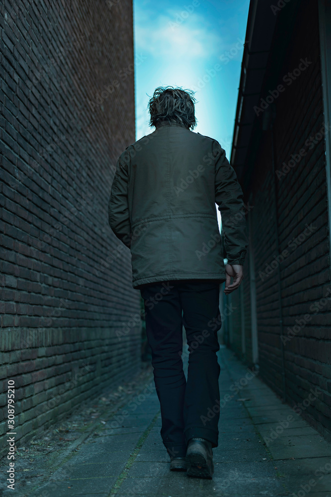 Man walking in dark urban alley. Rear view. Man walking in dark urban alley. Rear view.