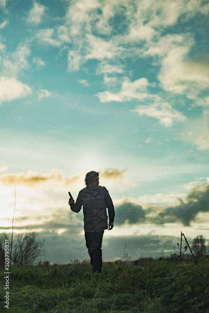 Man with handgun in countryside at sunset. Man with handgun in countryside at sunset.