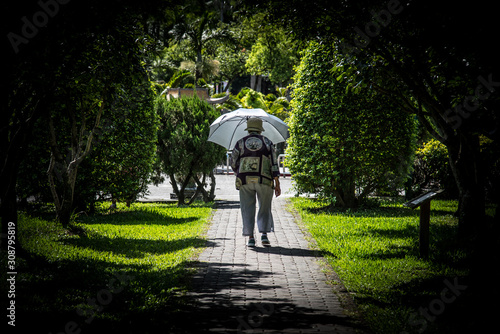 Frau mit Sonnenschirm geht im Park spazieren