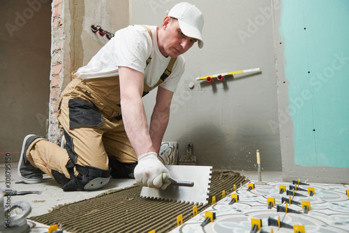 Tiler installing tile on bathroom floor. home indoors renovation photo