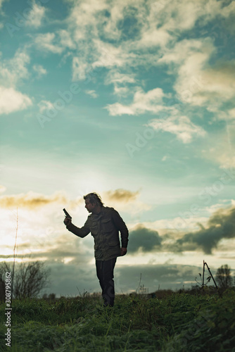 Man with handgun in countryside at sunset. © ysbrandcosijn