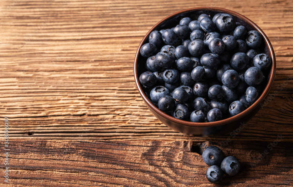 Fresh ripe blueberries in brown ceramic bowl on wooden background, ingredients for healthy diet lifestyle concept, 45 degree angle view, landscape horizontal format, copy space Fresh ripe blueberries in brown ceramic bowl on wooden background, ingredients for healthy diet lifestyle concept, 45 degree angle view, landscape horizontal format, copy space