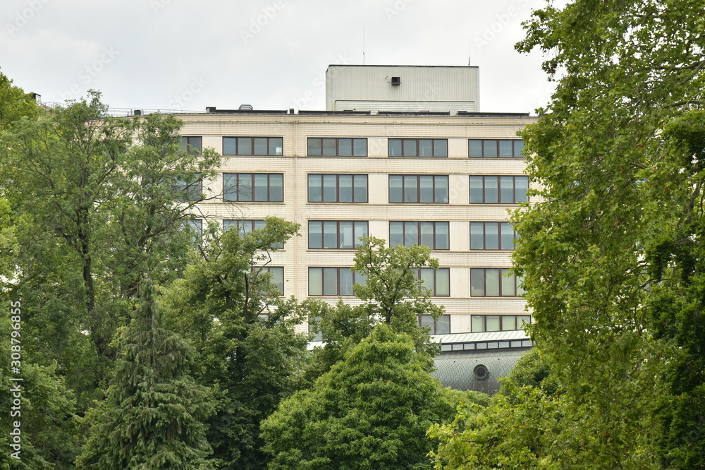 Bâtiment abritant des bureaux émergeant du feuillage des arbre du parc Léopold à Bruxelles