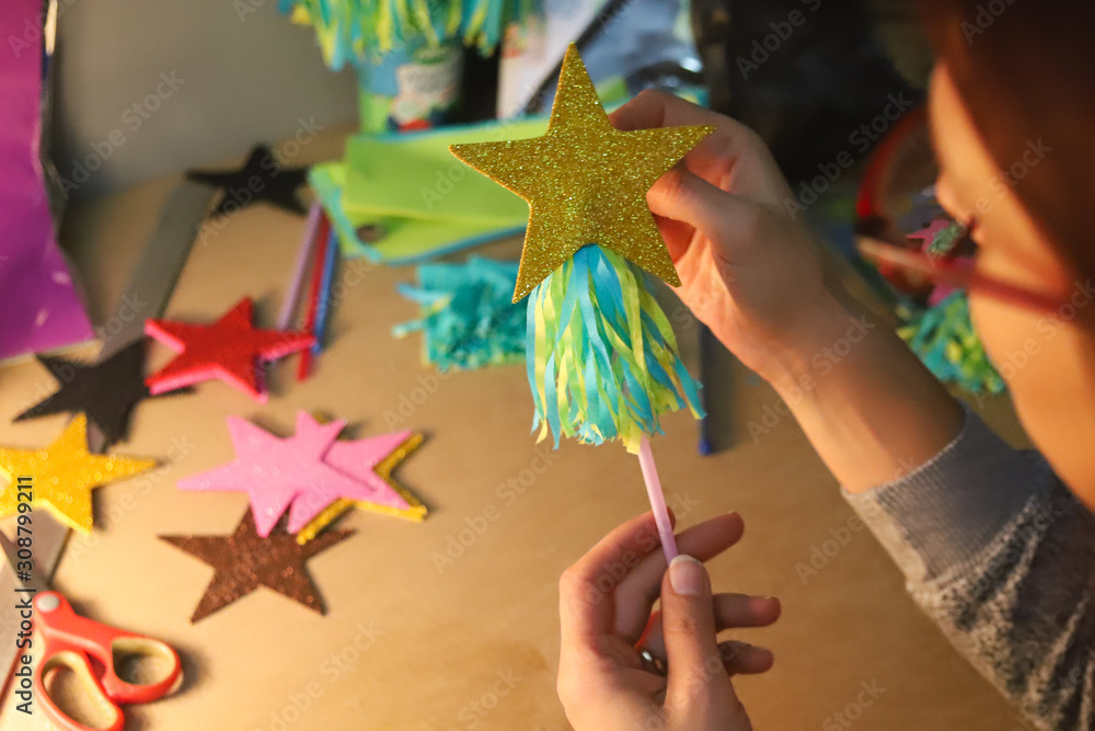 Obraz premium woman glues paper details on a plastic rod. Glue, paper, scissors on a wooden table. Children's art project, a craft for children