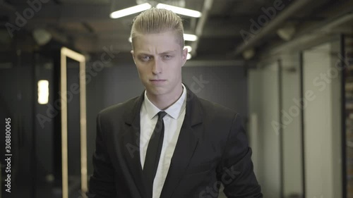Wallpaper Mural Camera approaching serious redhead man in elegant black formal suit standing in open space corridor. Male office worker looking at camera and holding document folder. CEO, management. Torontodigital.ca