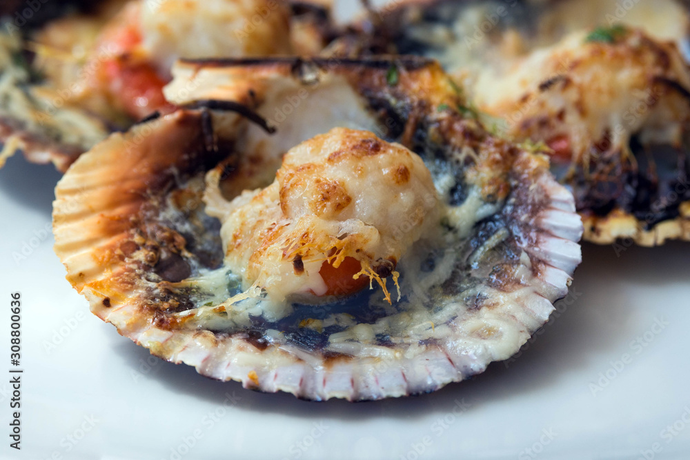 Baked scallops with cheese and spicy sauce. Delicate clam is a real pleasure. Romantic dinner at a Spanish fish restaurant. Mallorca Island, Spain. Baked scallops with cheese and spicy sauce. Delicate clam is a real pleasure. Romantic dinner at a Spanish fish restaurant. Mallorca Island, Spain.