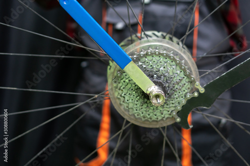 mountain bike repair. Bike mechanic in the workshop. Replacement of the rear wheel cassette. Dirty wheel, hub and spokes and worn folding tire. Professional tool for working with a bicycle.