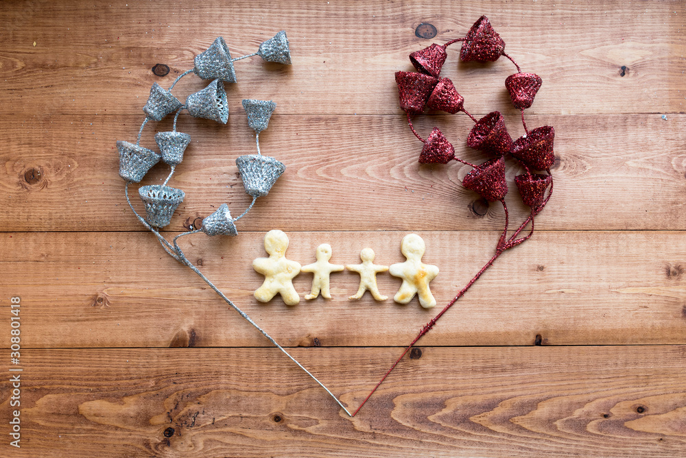The image of a loving family. Figures of people from the dough framed by shiny jewelry on a wooden background. Valentine's Day. Selective focus. Place for text. The image of a loving family. Figures of people from the dough framed by shiny jewelry on a wooden background. Valentine's Day. Selective focus. Place for text.