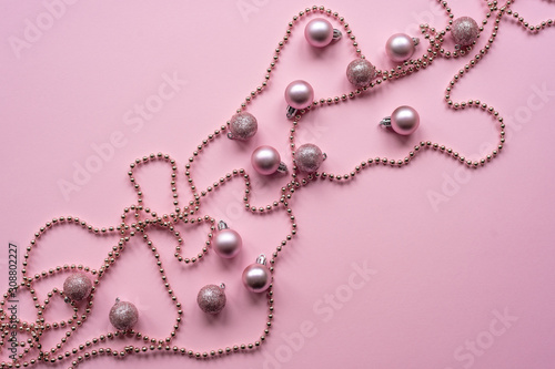 Christmas balls and garland on a pink background, New Year concept. Top view, flat lay.