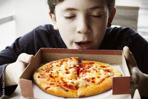 preteen handsome boy smell pizza in box