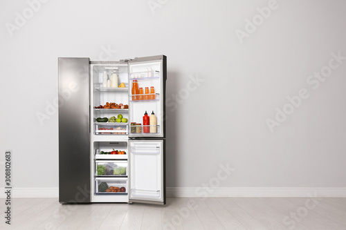 Open refrigerator filled with food indoors, space for text