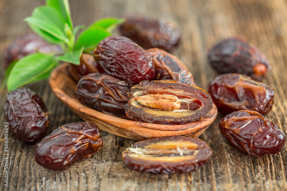 Juicy dates in a bowl on a old wooden table . Juicy dates in a bowl on a old wooden table .
