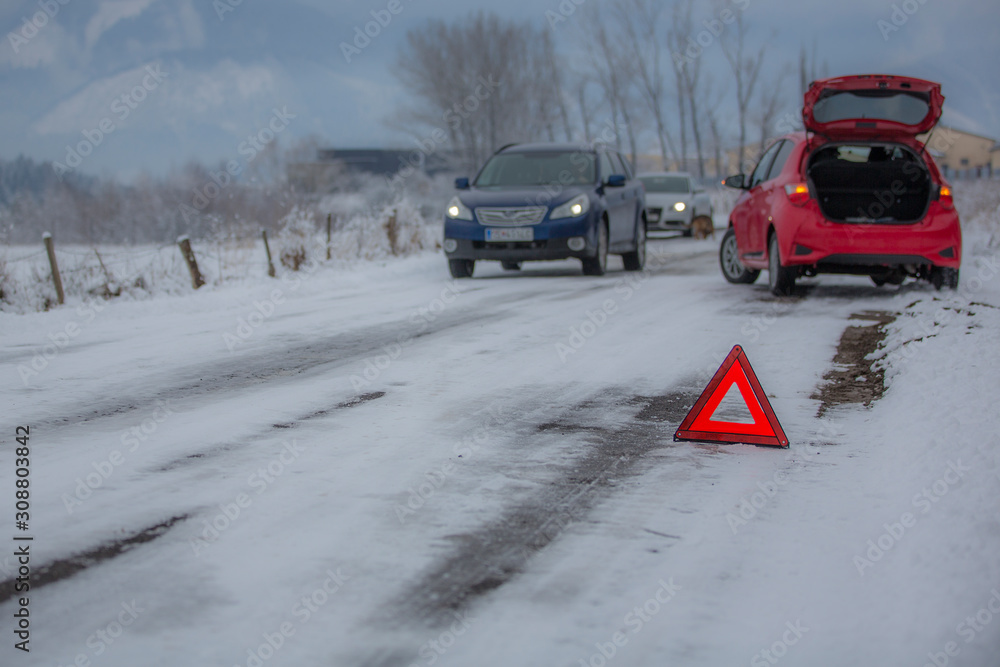 Broken car and warning triangle on the snowy winter road.