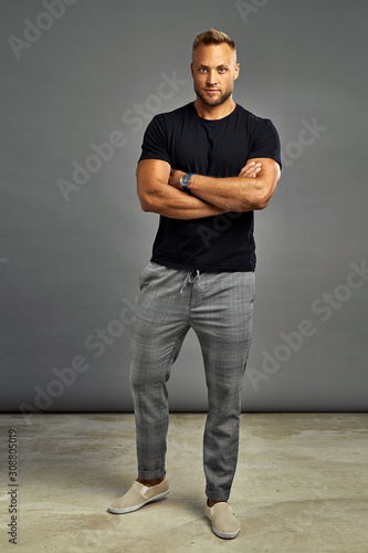 Handsome man posing with watch and looking at camera, isolated on gray background