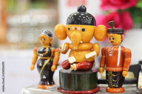 Selected Focus on Colorful Channapatna Toys of Lord God Ganesha and Man and Woman with Blurred Background