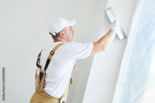 Painter with putty knife. Plasterer smoothing esconson surface at home renewal photo