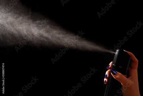 The dispersion jet from an aerosol can in feminine hand