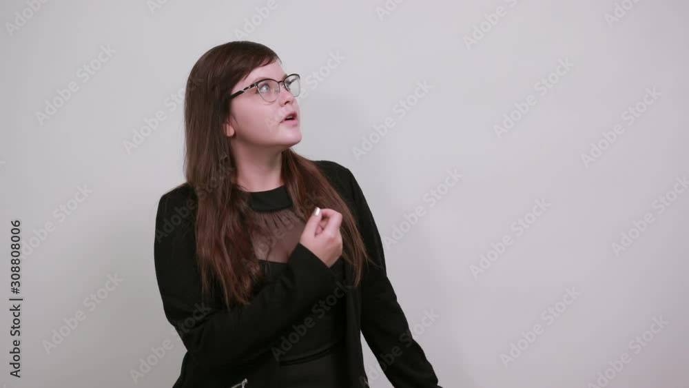 Portrait of cheerful young woman in nice clothes pointing finder aside, opened mouth isolated on gray wall background in studio. People sincere emotions, lifestyle concept. Portrait of cheerful young woman in nice clothes pointing finder aside, opened mouth isolated on gray wall background in studio. People sincere emotions, lifestyle concept.