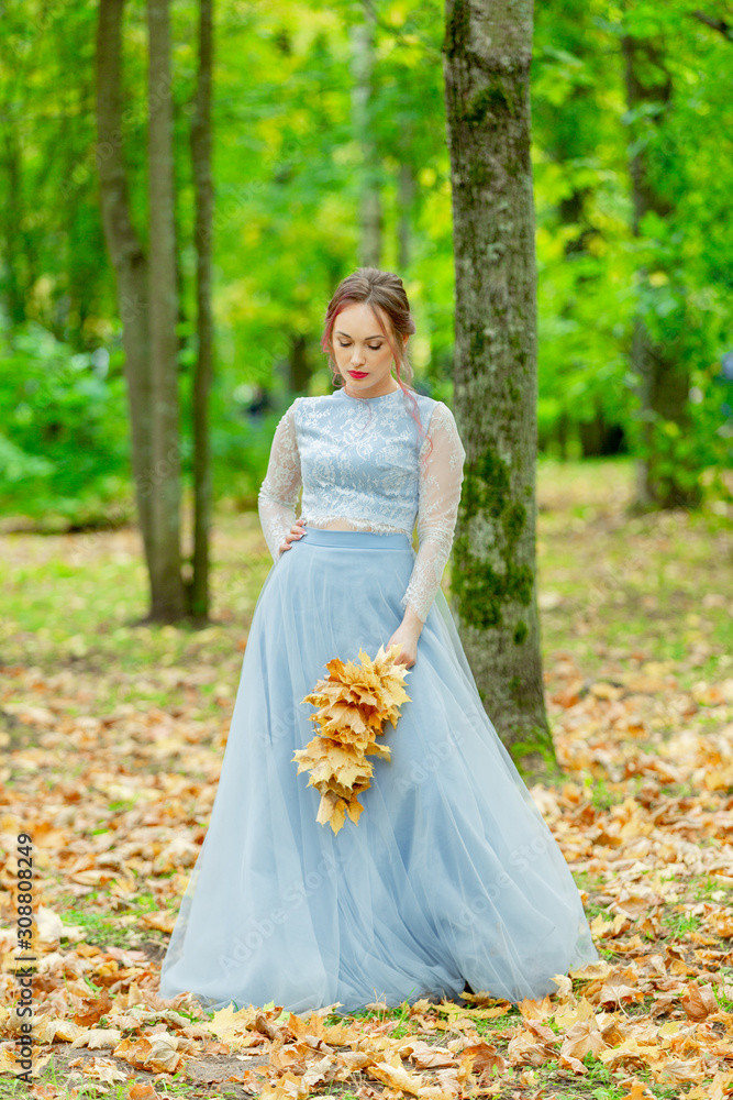 tender beautiful bride with a wreath of flowers on her head and in a wedding dress on a background of the autumn landscape