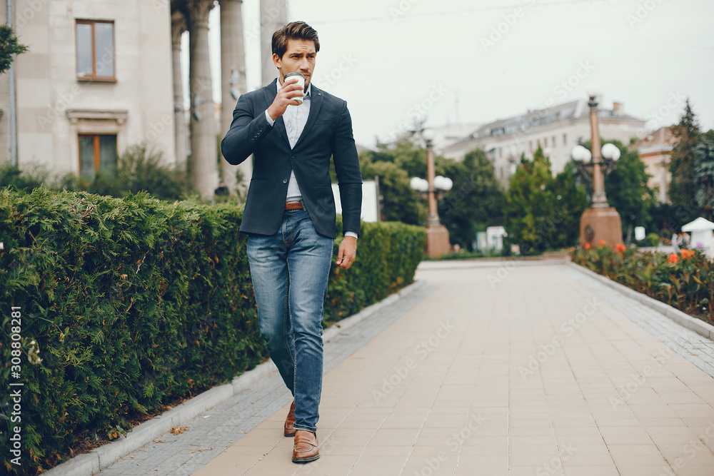 Man in a stylish suit. Businessman in a summer city. Male drinking a coffee