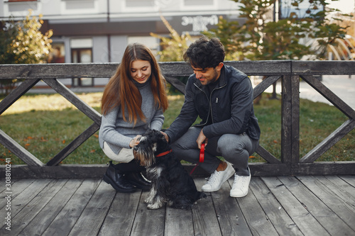 Cute couple in a spring city. Lady with long hair. Man in a black jacket. Two people with a dog