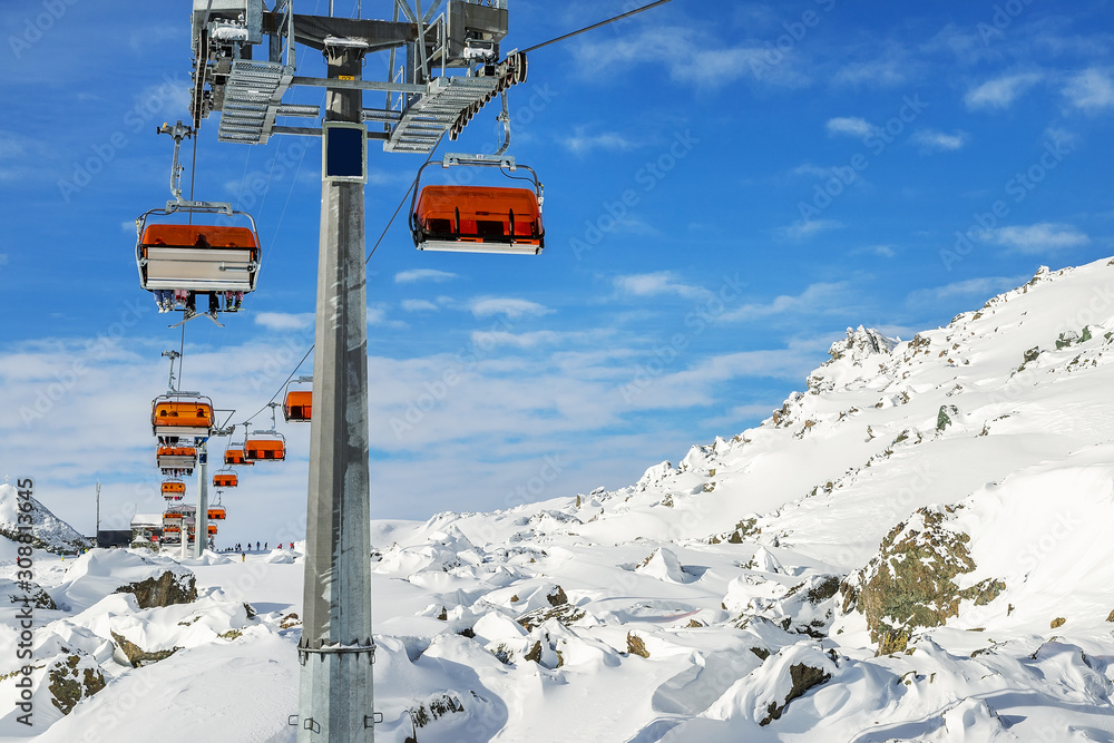 Ski lift ropeway on hilghland alpine mountain winter resort on bright sunny day. Ski chairlift cable way with people enjoy skiing and snowboarding. downhill slopes and virgin snow off-piste area Ski lift ropeway on hilghland alpine mountain winter resort on bright sunny day. Ski chairlift cable way with people enjoy skiing and snowboarding. downhill slopes and virgin snow off-piste area