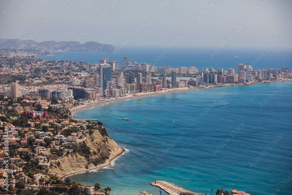 Beautiful super wide-angle aerial view of Calpe, Calp, Spain with harbor and skyline, Penon de Ifach mountain, beach and scenery beyond the city, seen from Mirador Monte Toix mountain viewpoint