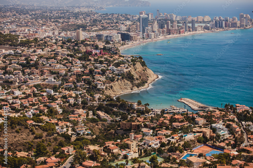 Fototapeta premium Beautiful super wide-angle aerial view of Calpe, Calp, Spain with harbor and skyline, Penon de Ifach mountain, beach and scenery beyond the city, seen from Mirador Monte Toix mountain viewpoint