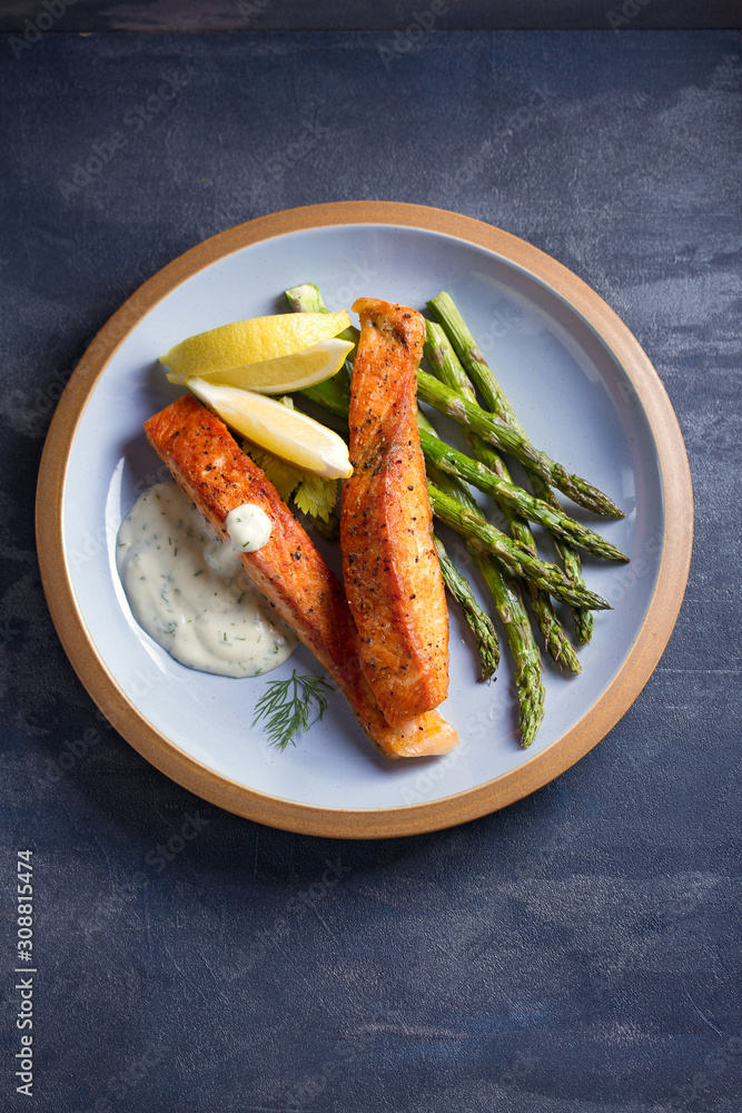 Delicious cooked salmon fish fillets with asparagus and lemon wedges Delicious cooked salmon fish fillets with asparagus and lemon wedges