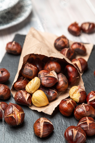 Roasted chestnuts in a paper bag, lying on a slate photo