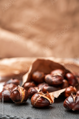 Roasted chestnuts in a paper bag, lying on a slate