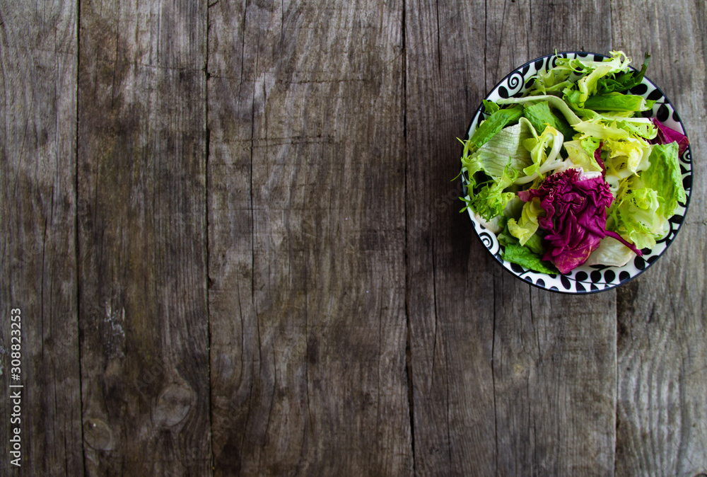 Plate of fresh green salad on wooden background. Free copy space.