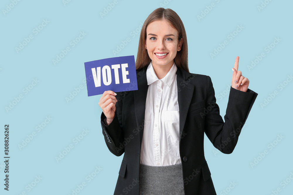 Young businesswoman holding paper with text VOTE on color background Young businesswoman holding paper with text VOTE on color background