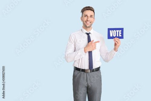 Businessman holding paper with text VOTE on color background