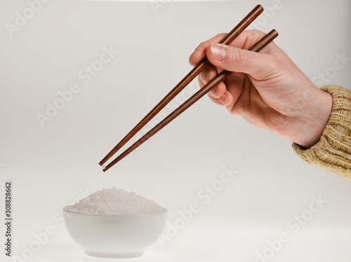 hand holding chopsticks isolated on gray 