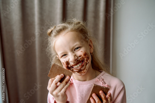 Little girl eating chocolate. a little girl smeared chocolate. a sweet chocolate holiday. dirty hands and cheeks. face in chocolate