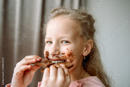 a little girl smeared chocolate. a sweet chocolate holiday. dirty hands and cheeks. face in chocolate.