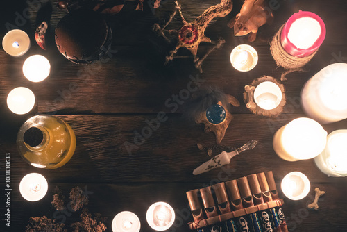 Witch doctor accessories in the light of burning candles on the wooden table background. The witchcraft concept.